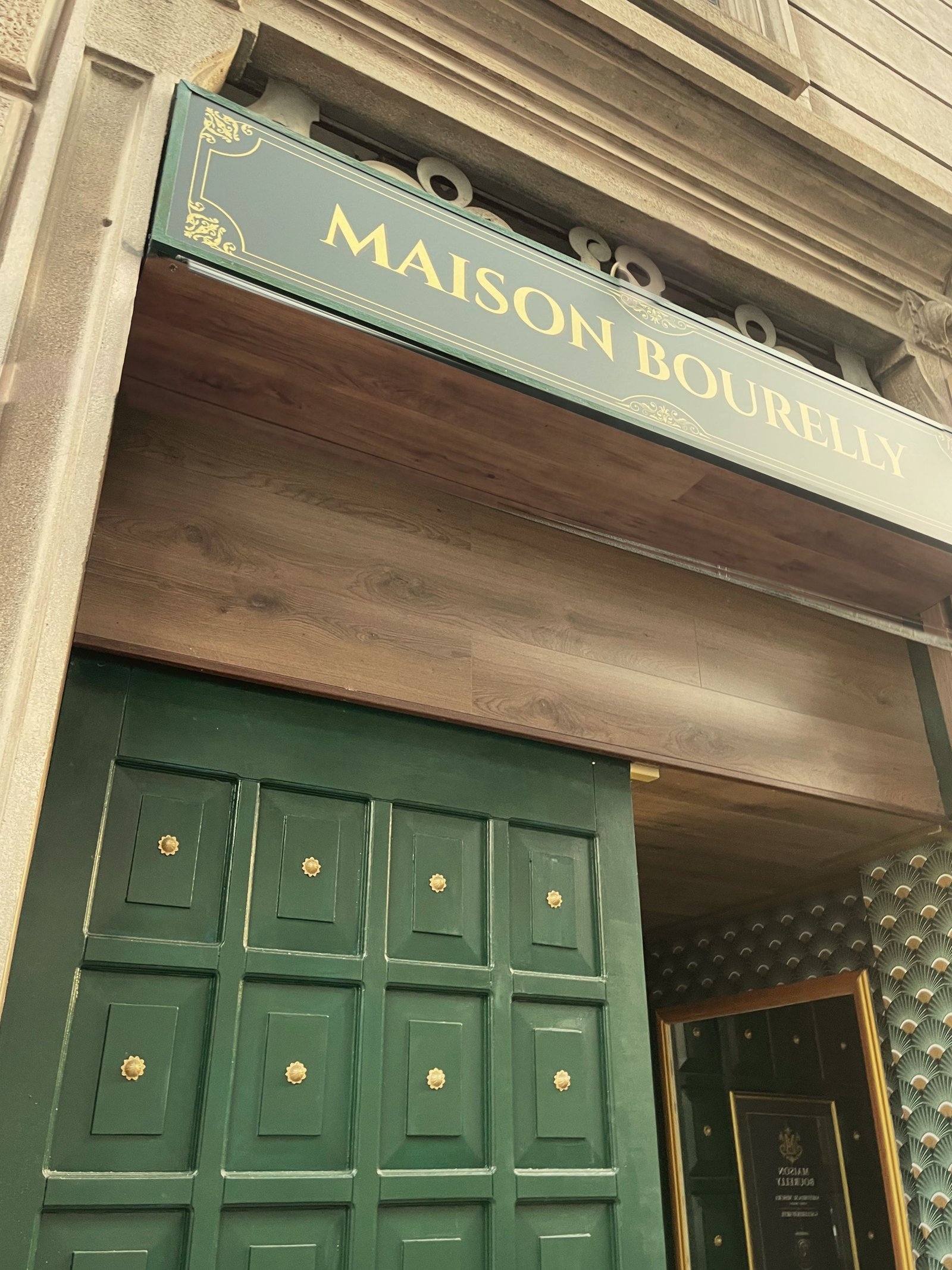 Ingresso dell’atelier Maison Bourelly a Milano, con l’insegna sopra il portone verde