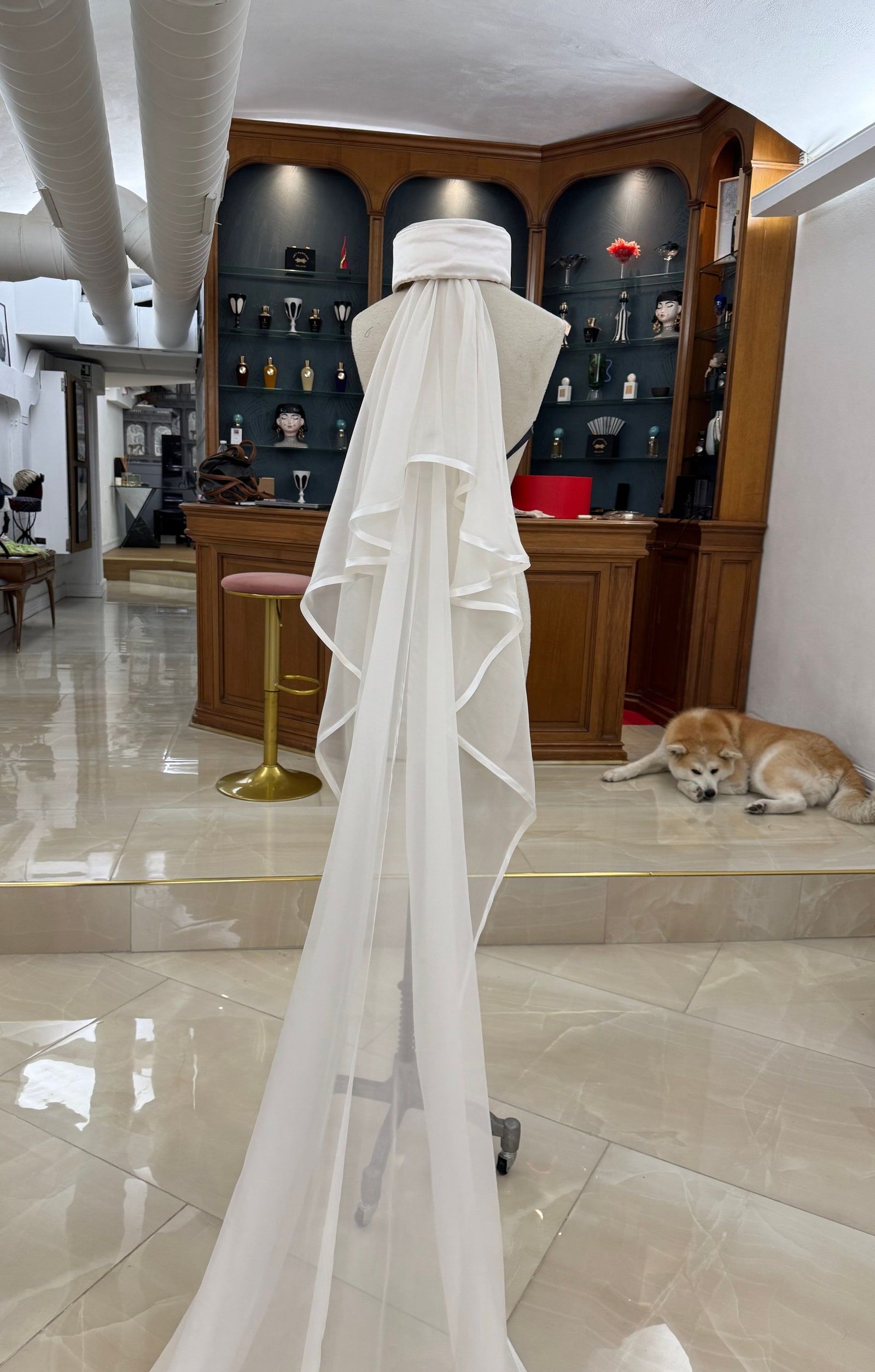 Un velo da sposa della Maison, lungo fino a terra, con la fascia coordinata, sul manichino in atelier